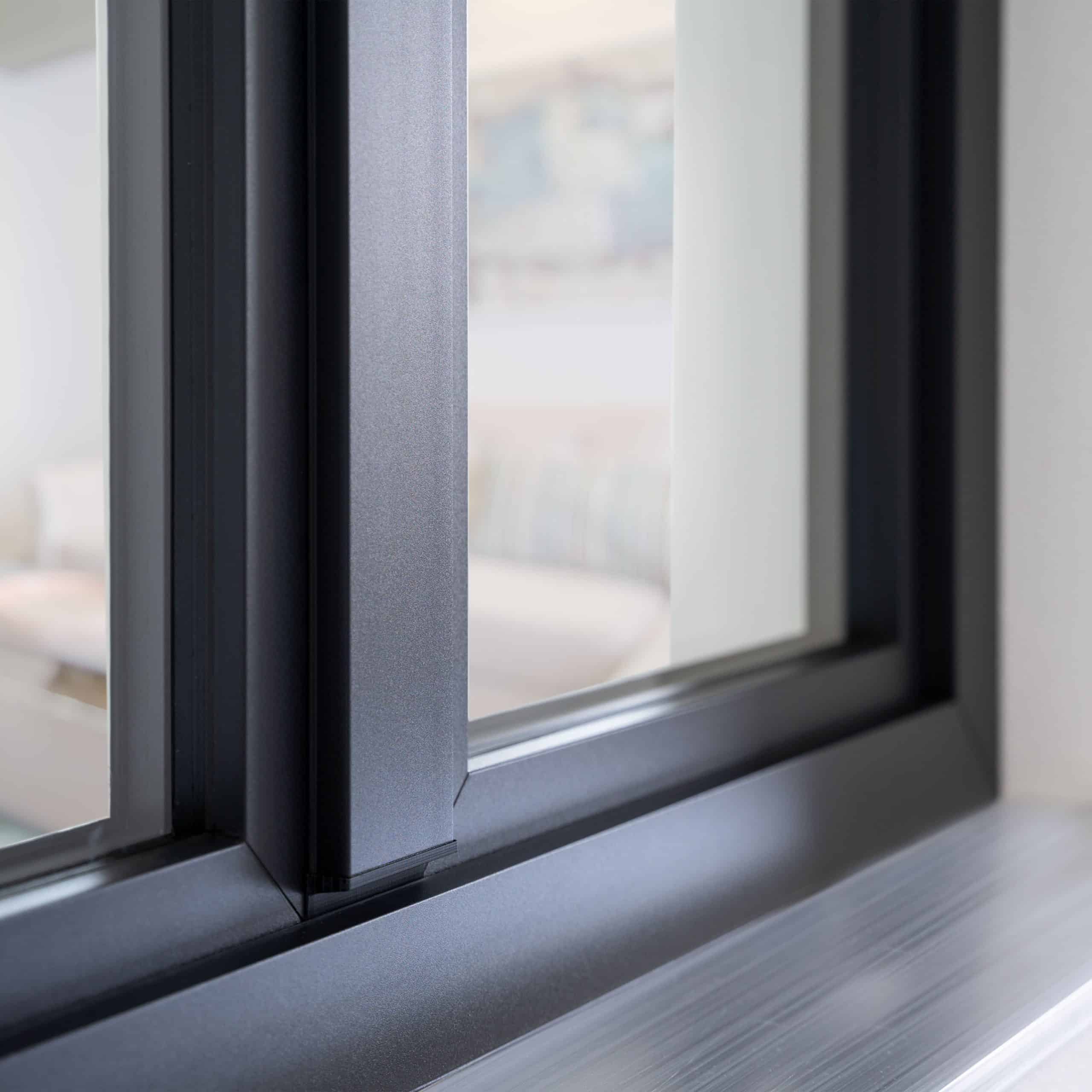 Nahaufnahme eines anthrazitgrauen Kunststofffensters LINEAR: Mittelpfosten, kantige Glasleisten und Fensterbank